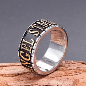Bague vintage en acier 316L avec relief Angel doré posée sur un décor d'écorce rustique