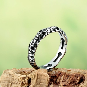 Vintage stainless steel skull ring with oxidized finish shown on a wood surface
