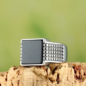 Close-up of vintage industrial stainless steel ring featuring a square black stone inlay