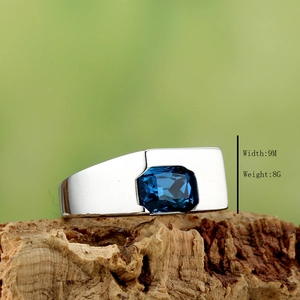 Macro detail of men's wide silver ring with rectangular blue gemstone on tree bark