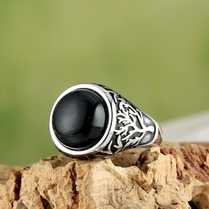 Macro detail of men's vintage silver ring with black stone and tree of life carvings