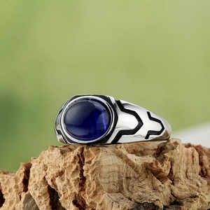 Macro detail of men's vintage titanium steel ring with oval blue gemstone on cork base