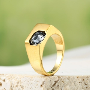 Macro view of gold zircon ring with rectangular black gemstone on stone surface