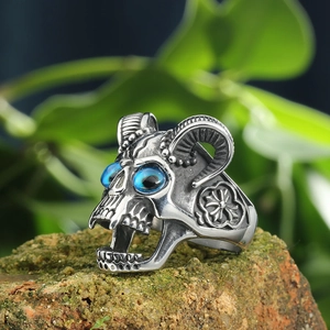 Vintage stainless steel skull sheep horn ring with blue gemstone on a mossy stone