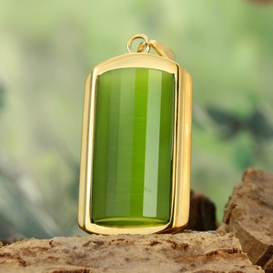 Macro detail of a rectangular green stone pendant with gold bezel on natural bark texture