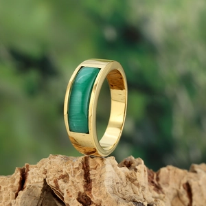 Detailed close-up of a golden stainless steel ring with a rectangular green gemstone