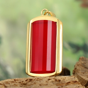 Macro view of rectangular red stone pendant with gold frame on a rustic wooden base