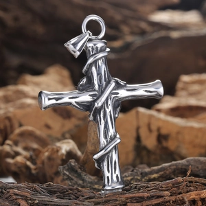 Retro stainless steel cross pendant with rose vine texture on a rustic wooden background