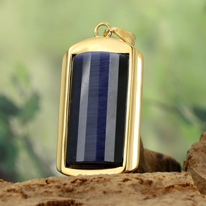 Detail of gold titanium pendant with vertical striped blue stone on wood base