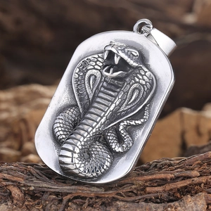 Macro view of stainless steel dog tag pendant featuring a detailed 3D king cobra relief