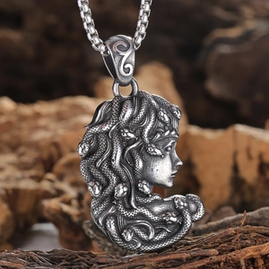 Vista macro del ciondolo Medusa con dettagli di capelli di serpente su legno