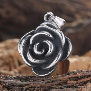 Macro shot of vintage silver rose pendant in stainless steel on a rustic wood bark base