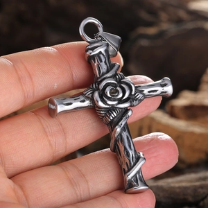Retro gothic silver cross pendant with rose flower details held in hand over wooden background