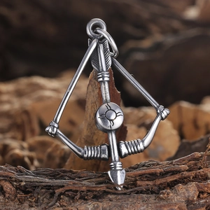 Gros plan sur un pendentif arc et flèche en acier inoxydable sur fond bois rustique