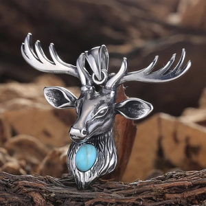 Detailed close-up of a vintage elk pendant with a blue turquoise stone on rustic wood