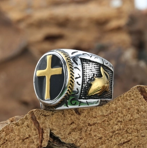 Vintage stainless steel ring with golden cross and praying hands on rustic wood