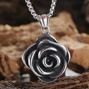Vintage stainless steel rose pendant necklace with a retro floral design on wood background
