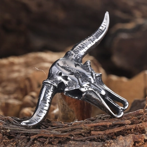Detailed view of vintage bull skull pendant on textured bark background