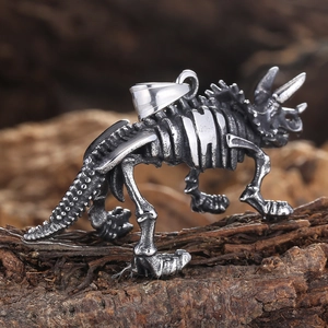 Vintage silver triceratops skeleton pendant on dark wood background, 45-degree angle