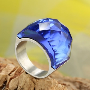 Makroaufnahme eines großen facettierten blauen Edelsteinrings auf Naturholzstruktur