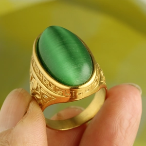 Macro detail of vintage gold ring with large oval green cat eye stone and relief carving