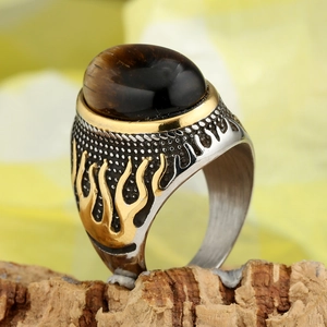 Macro shot of retro punk men's ring with brown tiger eye stone and gold flame detail