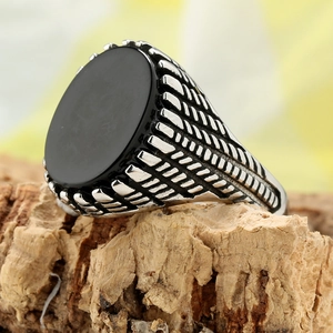 Vintage titanium steel ring with black oval stone and textured band on wood base