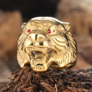 Punk style golden tiger head ring with red gem eyes on a rustic wood background