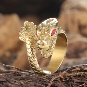 Macro detail of vintage gold dragon ring featuring intricate scales and red gem eyes