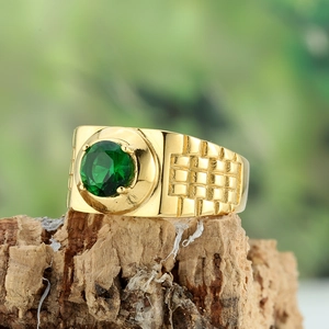 Titanium steel ring with round green gemstone and gold textured band on wood