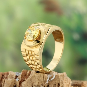 Detailed macro view of a gold-toned men's ring with a yellow gemstone and textured band