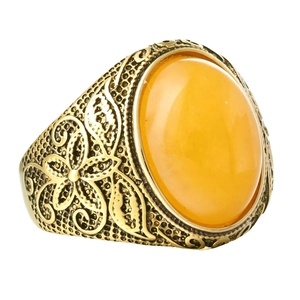 Dettaglio macro di anello vintage dorato con gemma ovale gialla e motivi floreali a rilievo