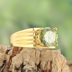 Detail of wide gold wave ring with olive green gemstone set on rustic tree bark