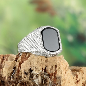 Men's vintage stainless steel signet ring with black stone on natural wood bark