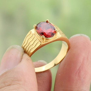 Macro detail of wave-textured titanium steel ring with oval red zircon in 4-prong setting