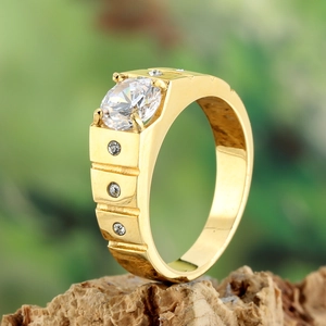 Bague large dorée classique avec un grand zircon central sur un support en bois