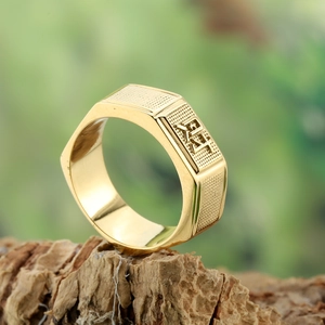 Close-up of golden hexagonal ring with relief symbol on a natural bark base