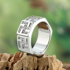 Macro shot of silver vintage swastika pattern wide ring on natural wooden block