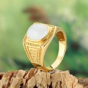 Macro detail of men's gold vintage ring with white stone inlay on natural wood bark