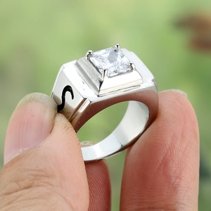 Macro shot of silver men's wide band ring with square zircon and black letter detailing