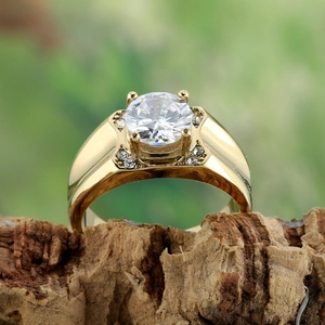 Polierter goldener Titanring mit rundem Stein auf natürlichem Holzhintergrund