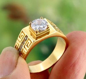Close-up of gold titanium ring with Greek meander relief and large round center stone