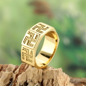 Golden stainless steel wide ring with swastika relief on rustic wood background