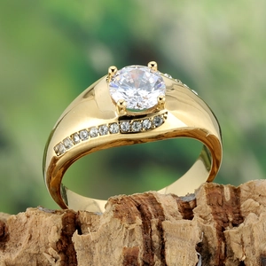 Vue rapprochée d'une bague dorée en titane avec un grand zircon sur un support bois