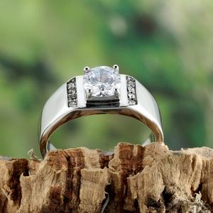 Macro detail of silver band ring with round cut gemstone on natural wood bark