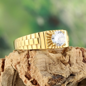 Macro view of gold ring featuring a large clear center stone and watch band texture
