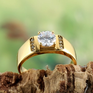 Macro detail of gold plated steel ring with round central stone on natural bark