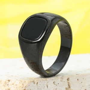 Close-up of a vintage black signet ring with a polished square stone on a stone prop