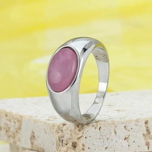 Polierter Edelstahlring mit ovalem rosa Naturstein auf einem Steinsockel platziert