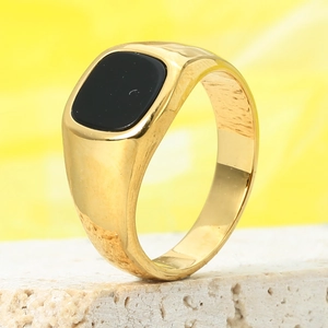 Macro view of men's gold signet ring featuring a rectangular black stone inlay